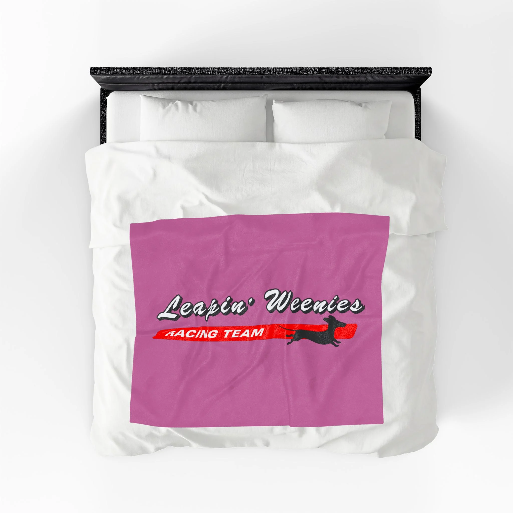 Top-down view of a bed with white sheets and a magenta panel featuring text and a running dog graphic (Leapin' Weenies Racing Team).